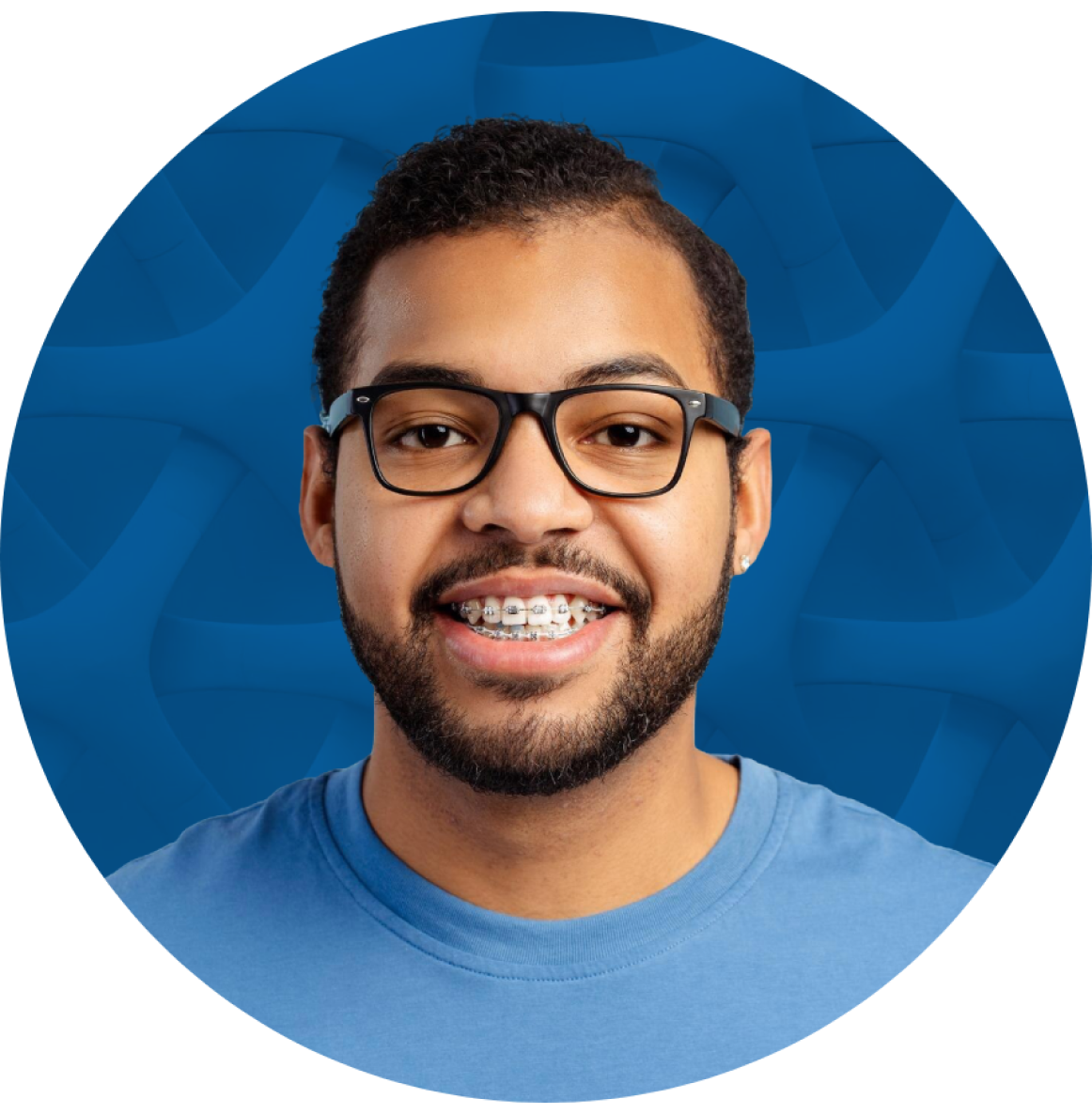 Man with glasses and braces smiling in front of a blue patterned background.