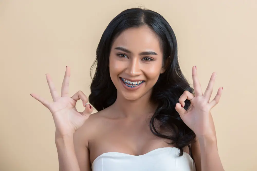 Beautiful woman face with metal braces doing ok sign