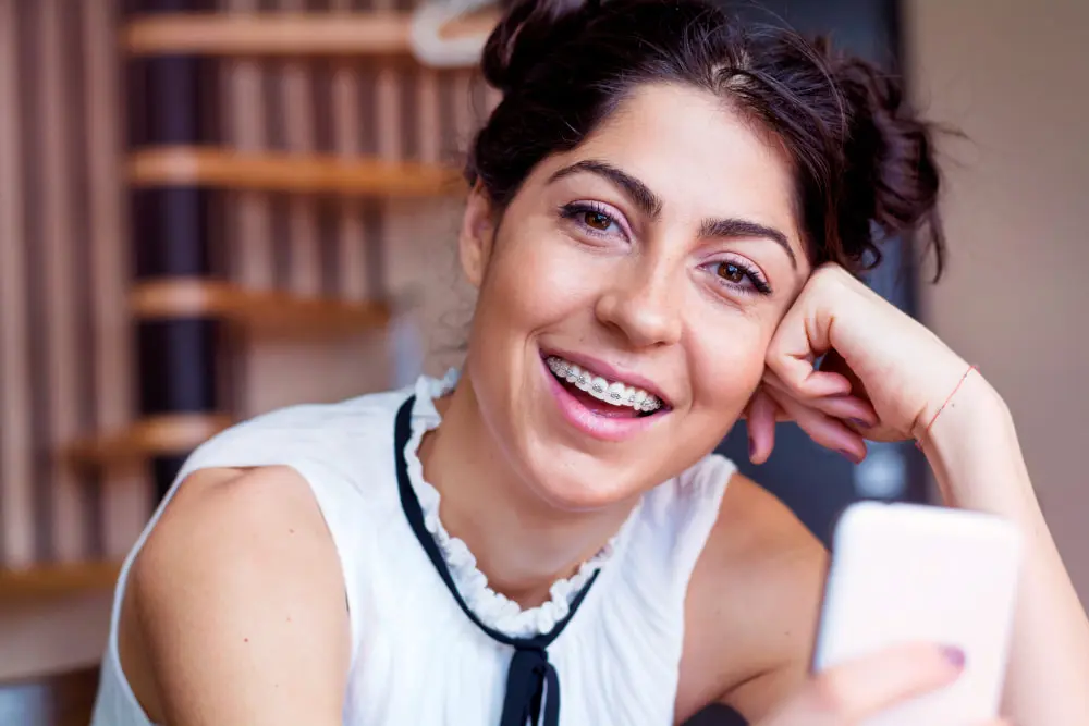 Close-up of woman wearing adult braces with her mobile