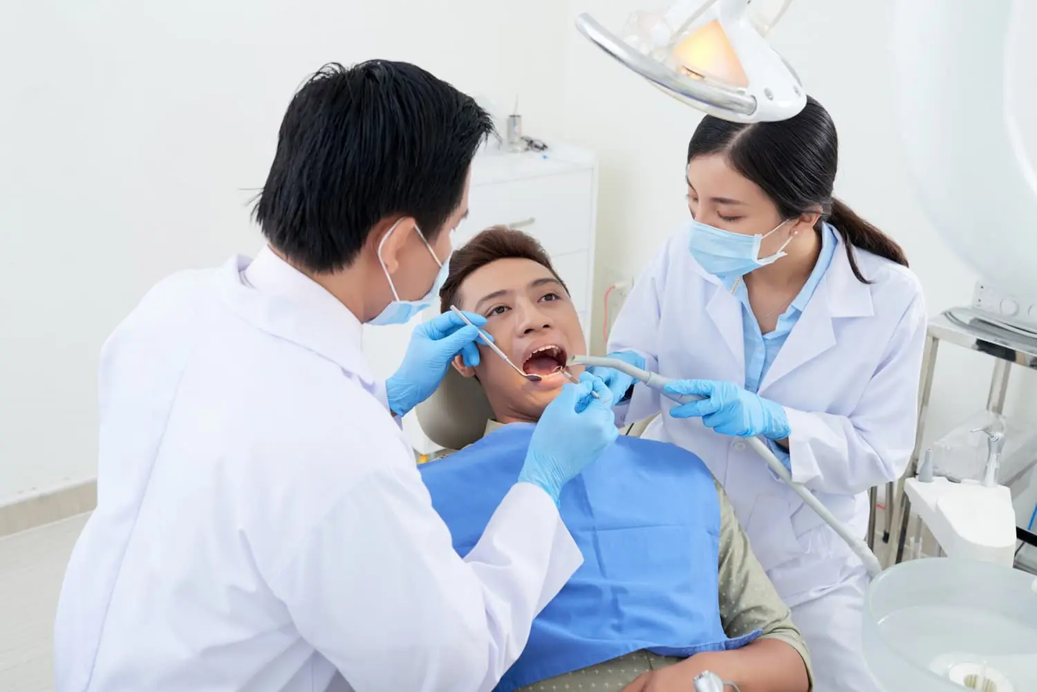 A dentist and dental assistant perform a dental check-up on a patient in a clinic.