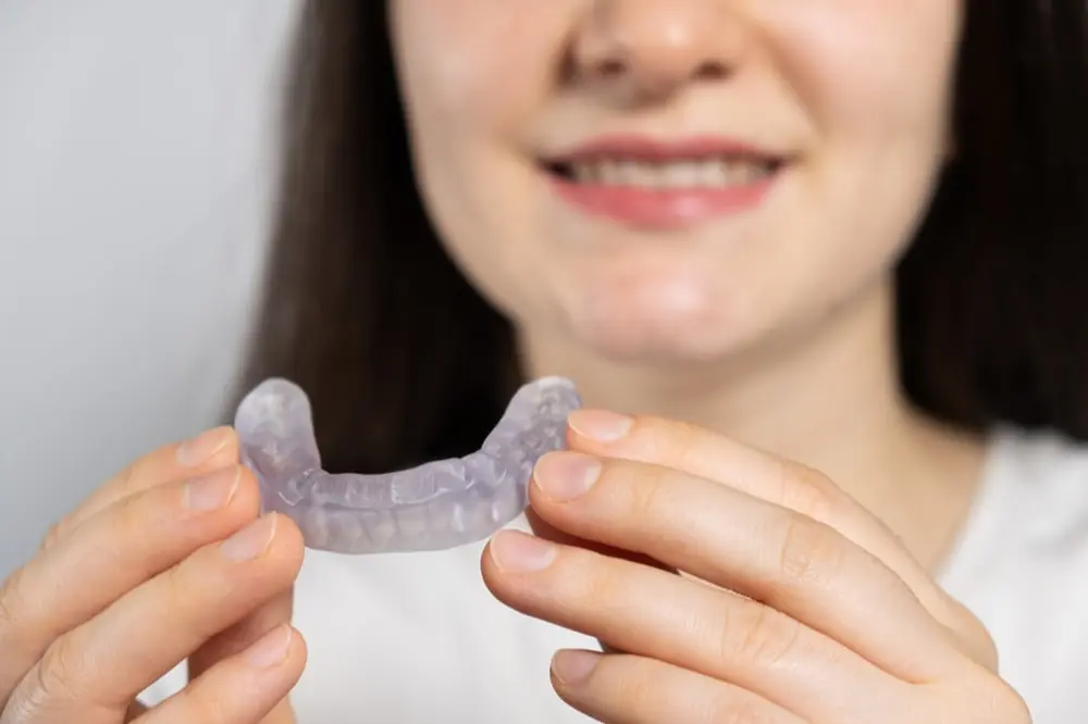 woman smiling holding tmj mouthguard